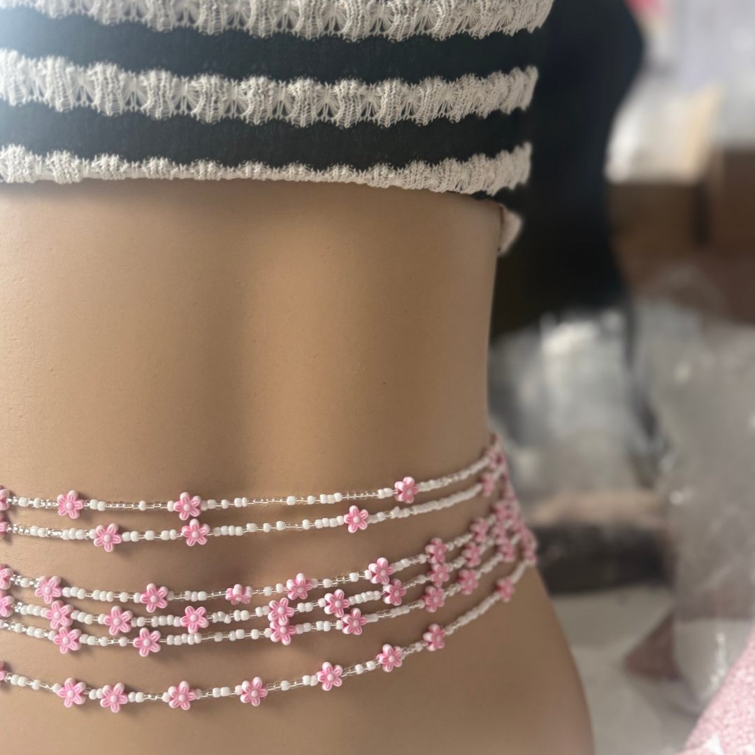 Close-up of a person wearing multiple beaded waistbeads with pink floral designs.