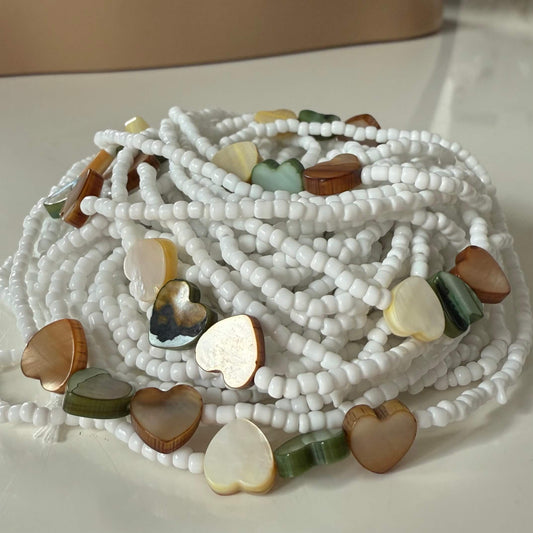 waist beads with white beads and heart-shaped multicolored stones on a light background